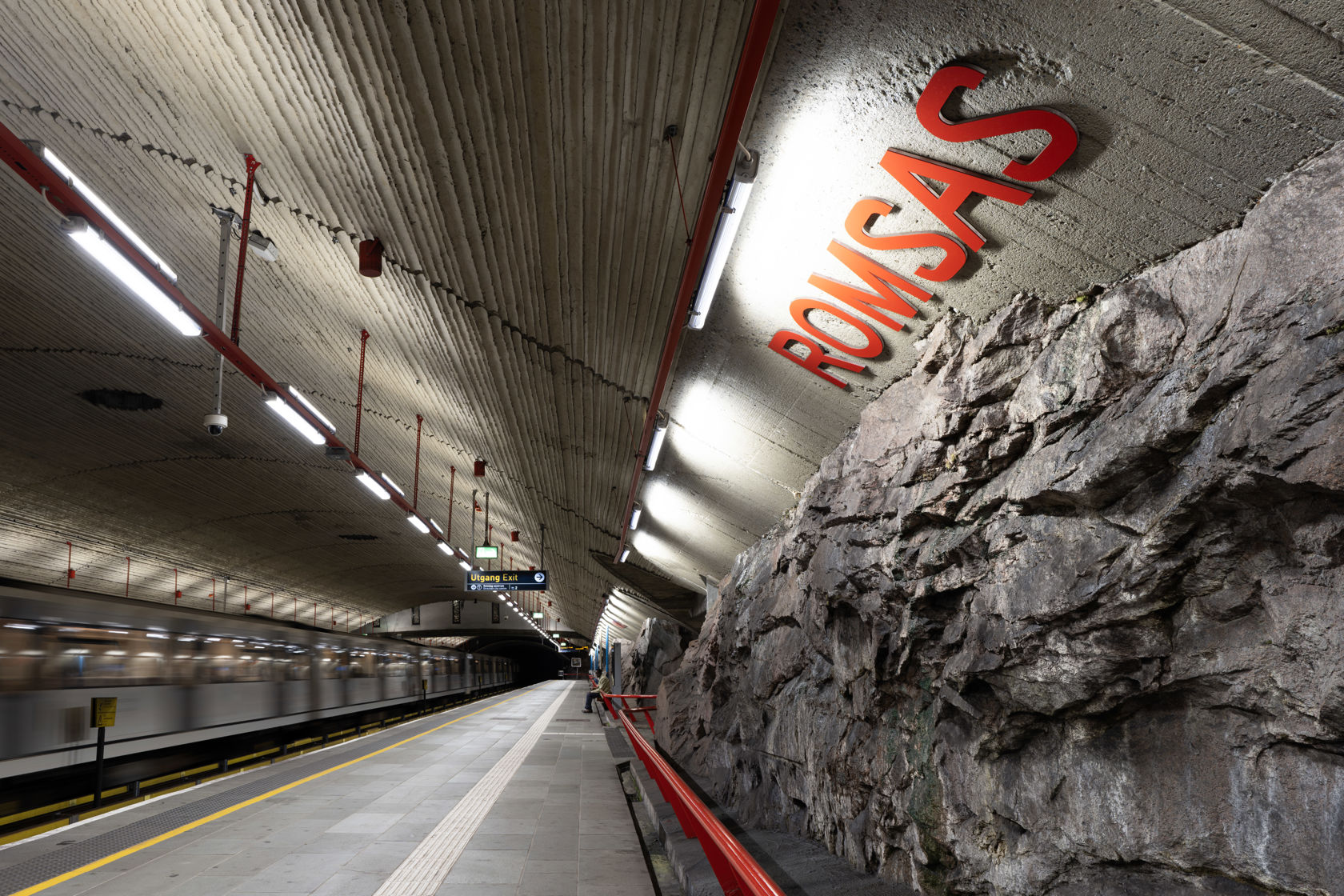 Plattform på Romsås T-banestasjon med stasjonsnavnet montert på den naturlige fjellveggen.