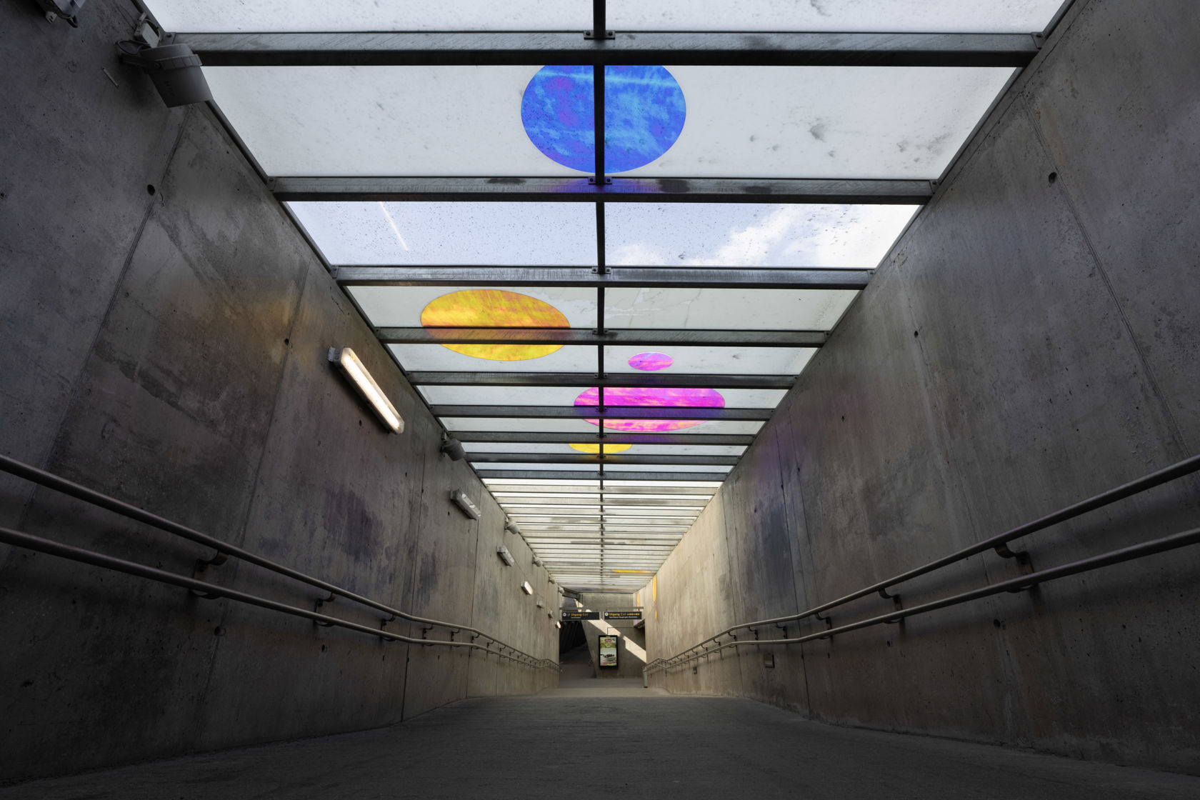 Adkomsttunnel på Sinsen T-banestasjon med glasstak og fargede glassfelt.