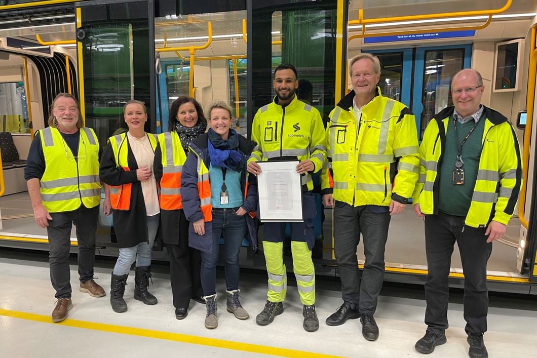 Prisvinneren (i midten) omgitt av representanter fra Fagforbundet, Sporveiens største fagforening OSA, og ledelsen i Sporveien ved blant annet trikkesjef Birte Sjule og Sporveissjef Cato Hellesjø. Foto: Sporveien